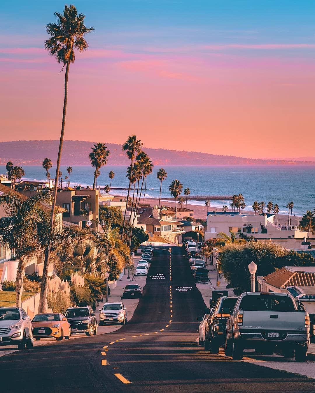 Coastal Neighborhood Street with Palm Trees and Ocean View at Sunset