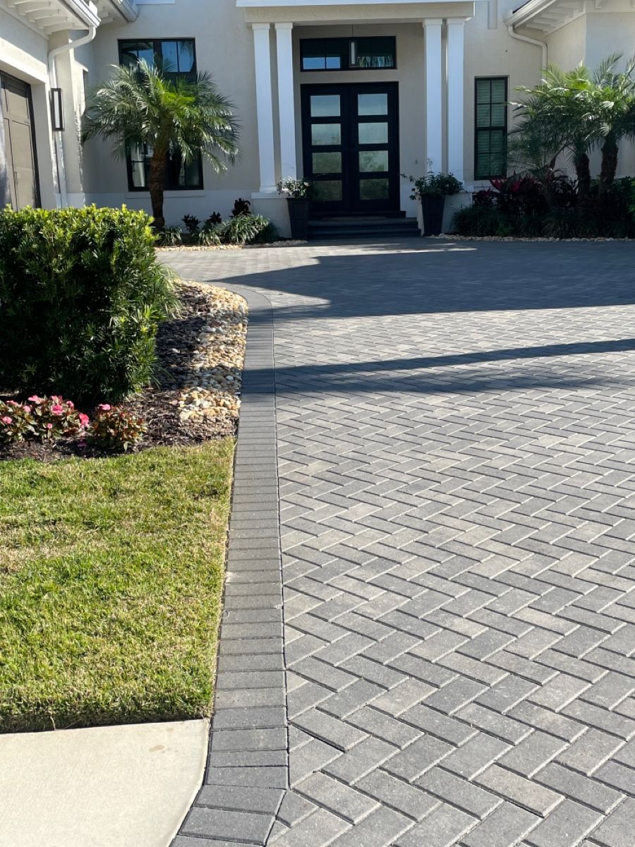 Modern Gray Paver Driveway with Herringbone Pattern and Lush Landscaping